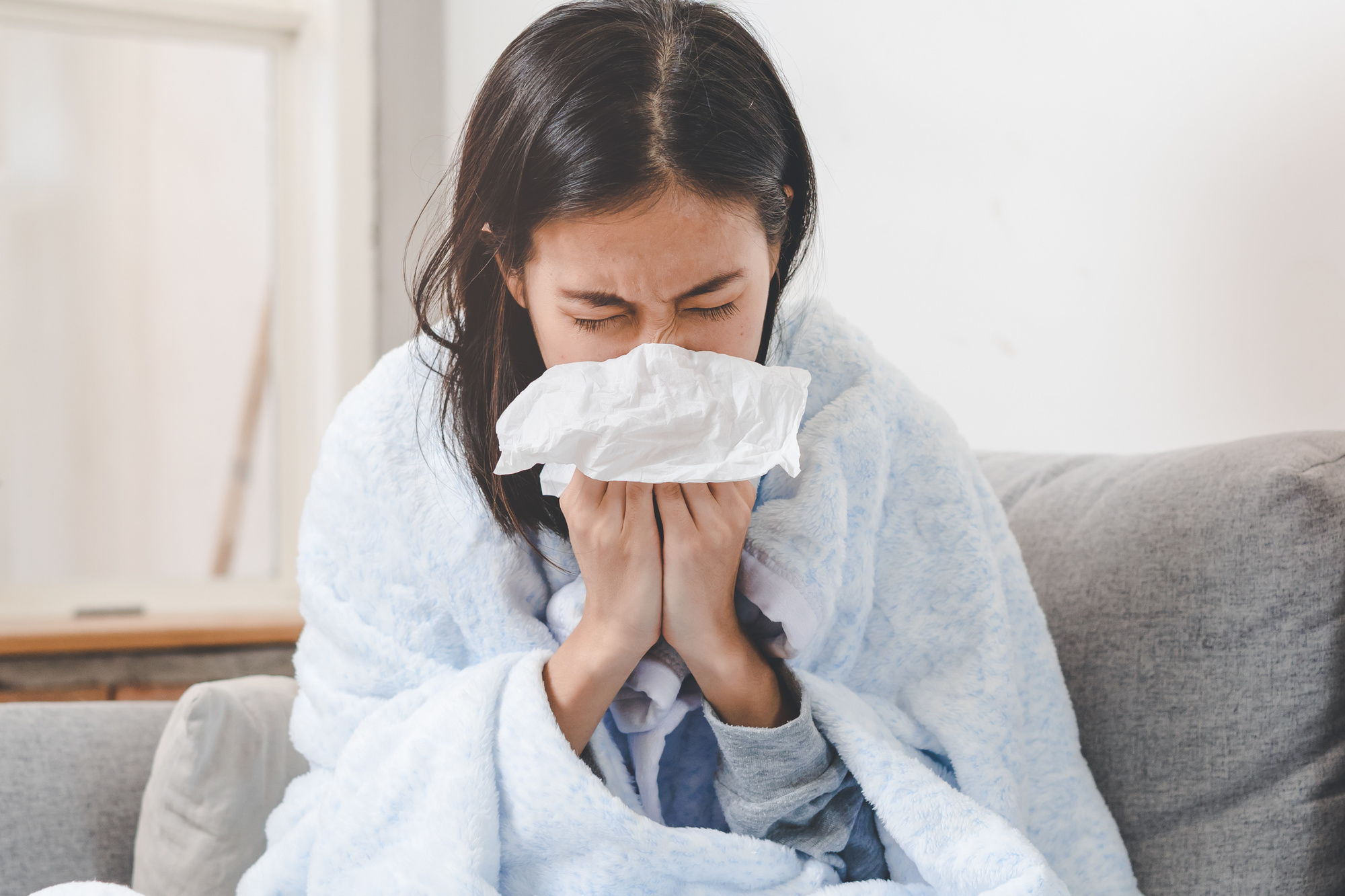 woman blowing her nose into a tissue
