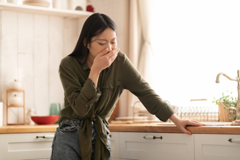 Woman in kitchen, thoughtful pose.