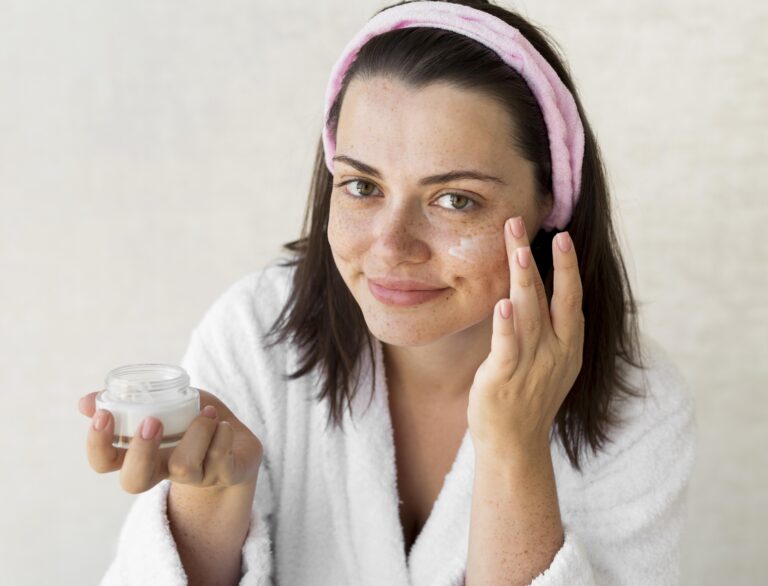 Woman applying face cream at home.